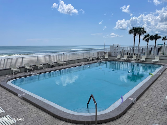 view of pool with a water view and a patio