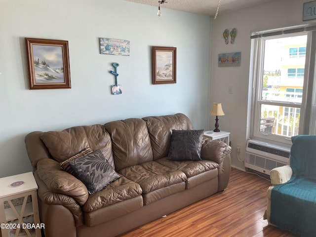 living room featuring a textured ceiling, a wealth of natural light, hardwood / wood-style flooring, and a wall mounted air conditioner