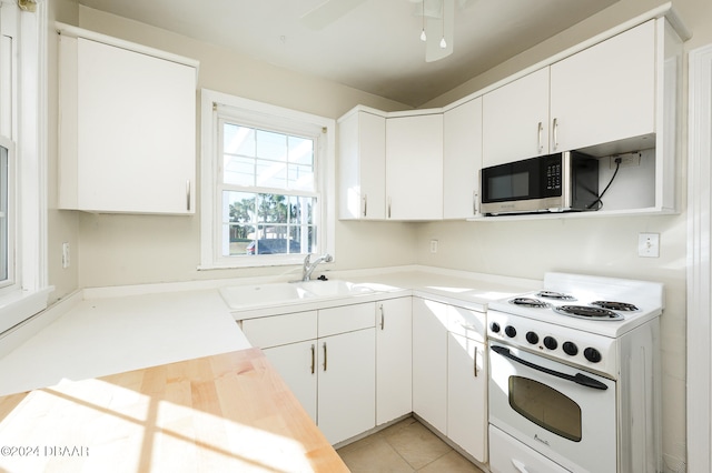 kitchen featuring light tile patterned flooring, white range with electric stovetop, sink, white cabinets, and ceiling fan