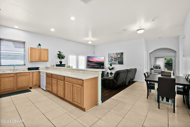 kitchen with kitchen peninsula, light tile patterned flooring, a wealth of natural light, and sink