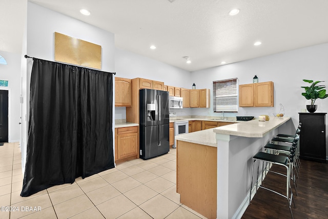 kitchen featuring a kitchen breakfast bar, white electric range, light tile patterned floors, kitchen peninsula, and fridge with ice dispenser