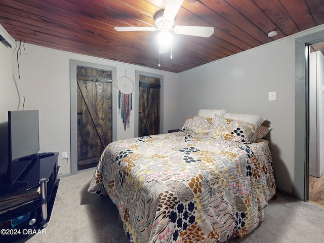 bedroom featuring light carpet, a barn door, ceiling fan, and wooden ceiling