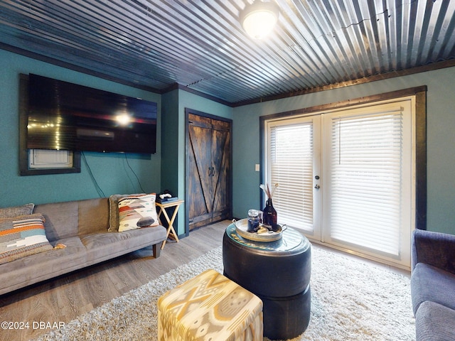 living room with a barn door, french doors, and hardwood / wood-style flooring