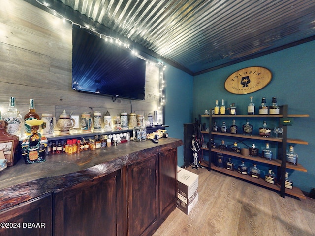 bar with light hardwood / wood-style floors and crown molding