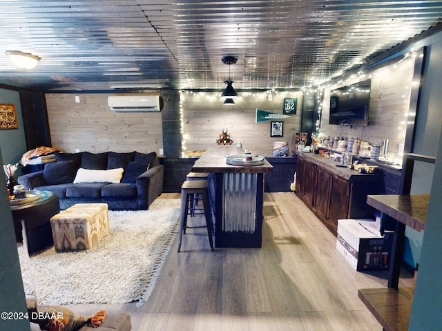 living room featuring bar area, wood walls, a wall unit AC, and light hardwood / wood-style flooring