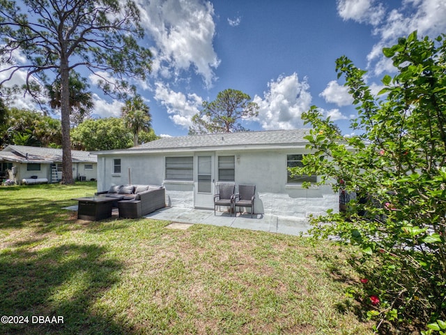 rear view of property featuring outdoor lounge area, a yard, and a patio