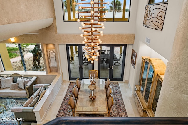 interior space featuring an inviting chandelier, a high ceiling, and french doors