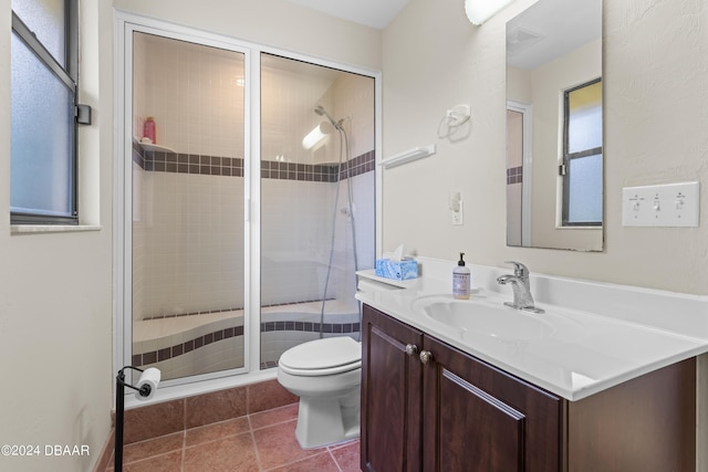 bathroom with tile patterned flooring, vanity, toilet, and a shower with door