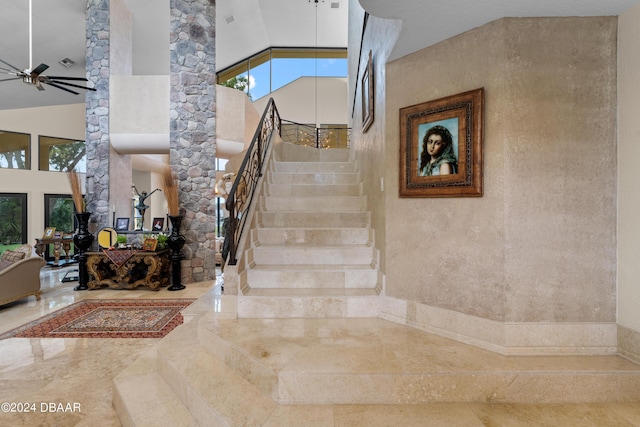 staircase with a towering ceiling and ceiling fan