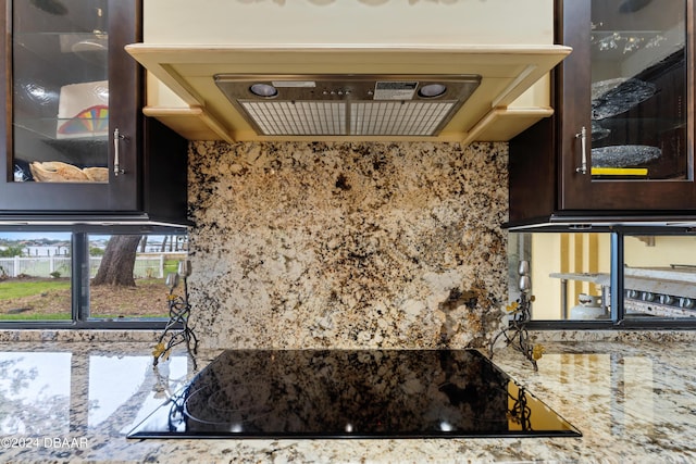 kitchen featuring black electric cooktop, light stone counters, and dark brown cabinets