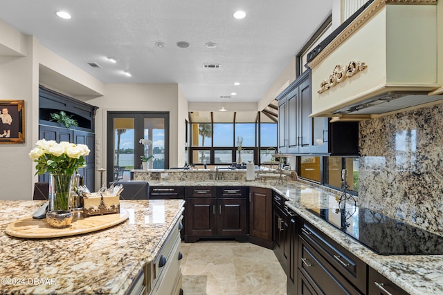 kitchen featuring backsplash, black electric cooktop, light stone counters, and a healthy amount of sunlight