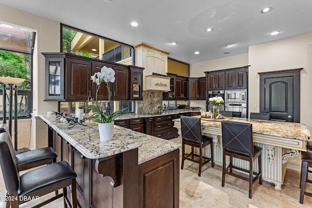 kitchen with light stone counters, a breakfast bar, stainless steel appliances, and dark brown cabinets