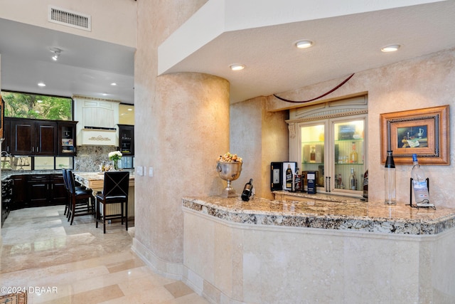 kitchen featuring dark brown cabinetry, light stone counters, and kitchen peninsula