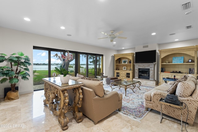 living room with a fireplace, a water view, and ceiling fan