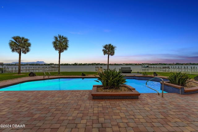 pool at dusk featuring a patio