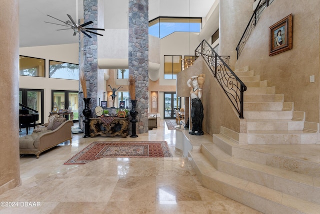 entrance foyer featuring a towering ceiling, decorative columns, and ceiling fan