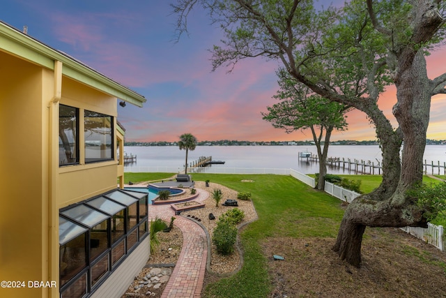 yard at dusk featuring a jacuzzi and a water view