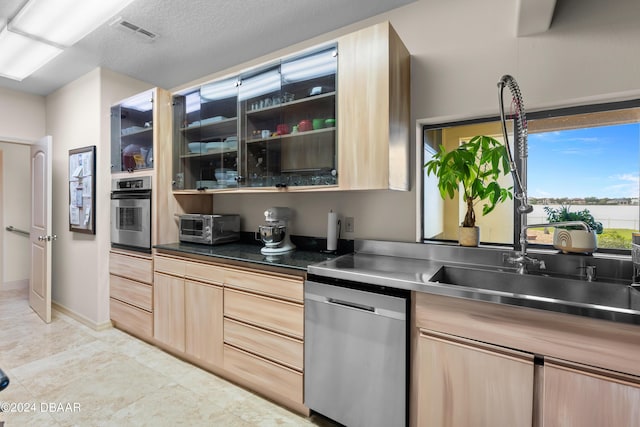 kitchen with appliances with stainless steel finishes, light brown cabinetry, and sink