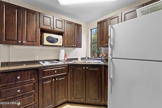 kitchen with dark brown cabinetry, white appliances, and sink