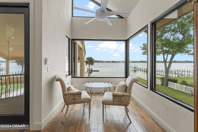 sunroom / solarium featuring ceiling fan and a water view