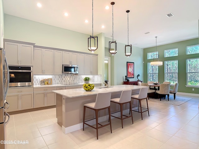 kitchen featuring stainless steel appliances, tasteful backsplash, a high ceiling, and visible vents