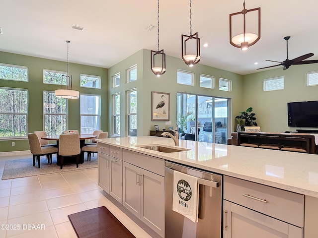 kitchen with light stone counters, light tile patterned floors, visible vents, open floor plan, and a sink