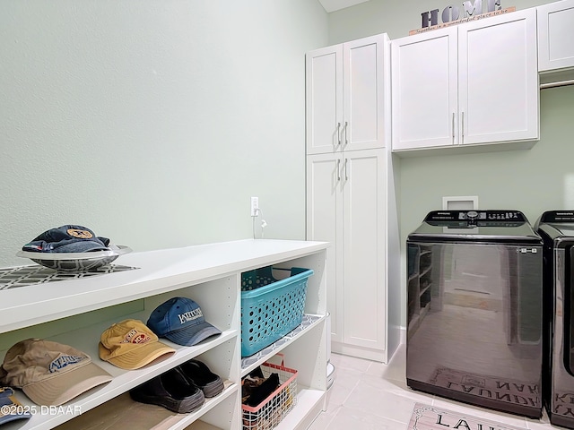 laundry room with light tile patterned floors, washing machine and clothes dryer, and cabinet space