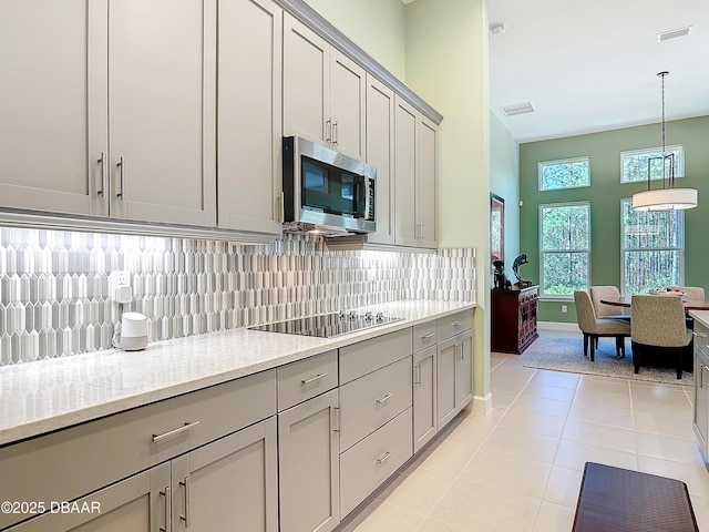 kitchen featuring black electric stovetop, gray cabinetry, visible vents, decorative backsplash, and stainless steel microwave