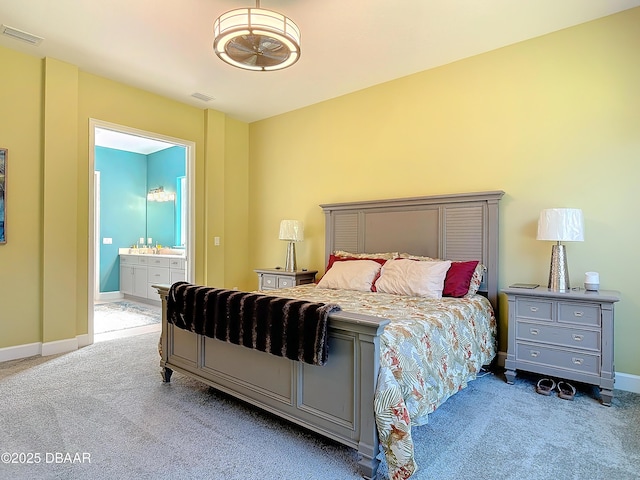 carpeted bedroom featuring ensuite bath, baseboards, and visible vents