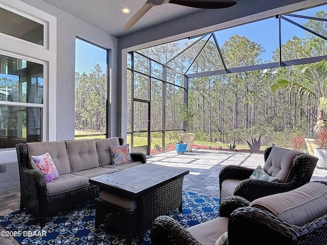 sunroom featuring ceiling fan and a view of trees