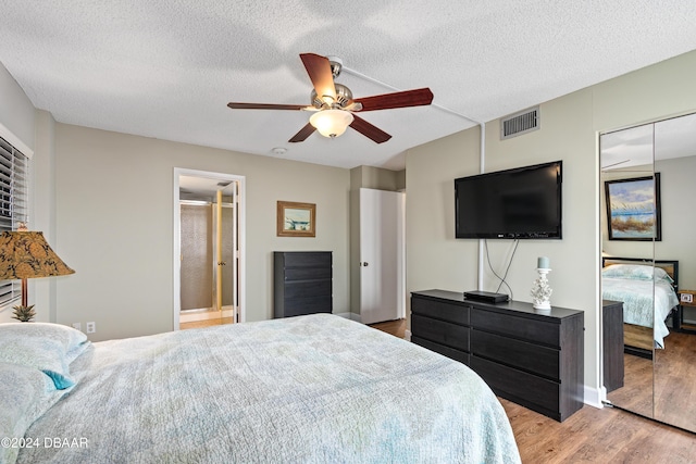 bedroom with ceiling fan, light hardwood / wood-style floors, and a textured ceiling