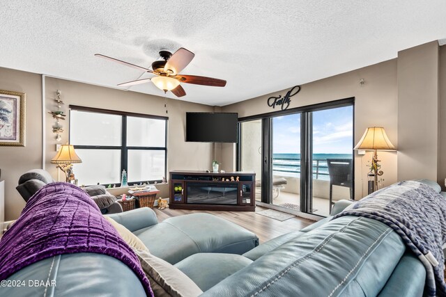 living room featuring ceiling fan, hardwood / wood-style flooring, and a textured ceiling