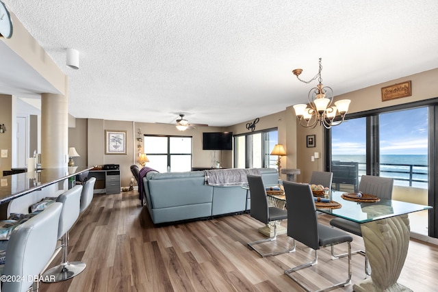 dining space featuring ceiling fan with notable chandelier, wood-type flooring, and a textured ceiling