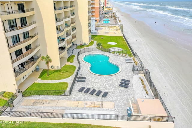 view of swimming pool with a patio, a water view, and a view of the beach