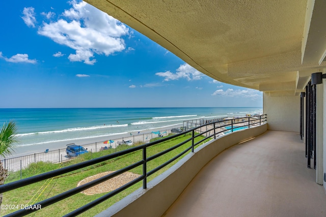 balcony featuring a water view and a beach view