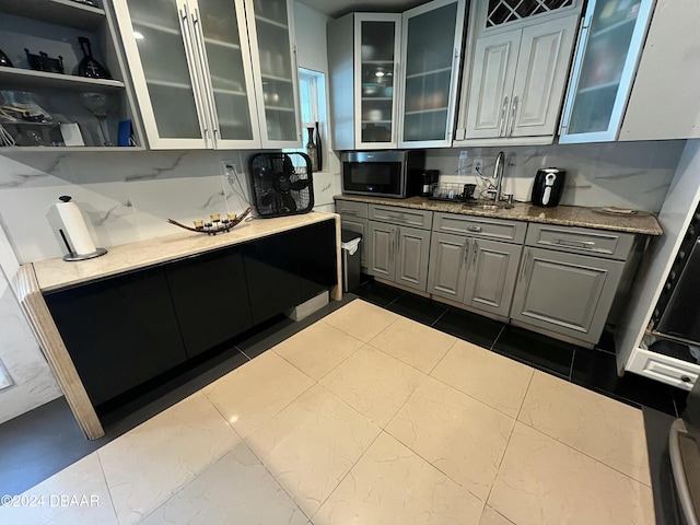 kitchen with gray cabinets, sink, and dark stone counters