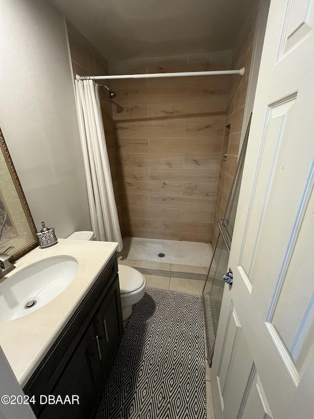 bathroom featuring tile patterned floors, vanity, toilet, and walk in shower