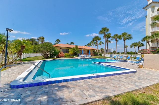 community pool with a patio area and fence