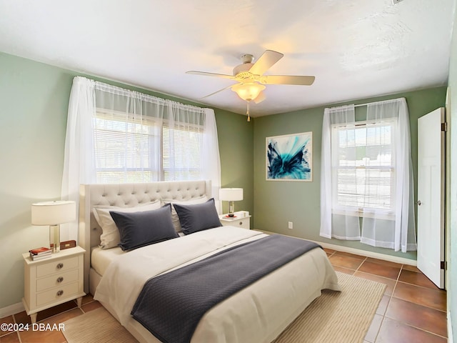 bedroom featuring tile patterned flooring, multiple windows, baseboards, and ceiling fan