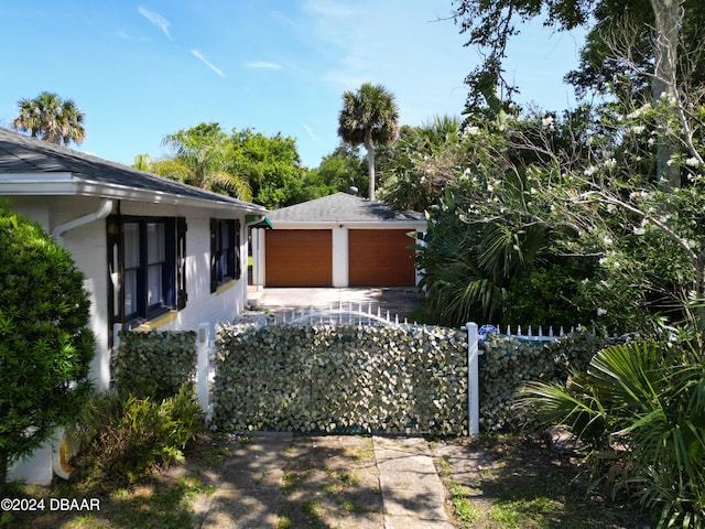 view of front of property featuring a shingled roof, fence, and stucco siding