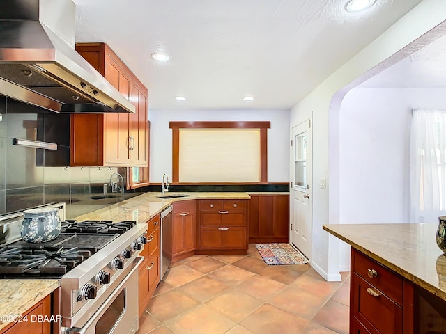 kitchen featuring stainless steel appliances, light stone countertops, a sink, and exhaust hood