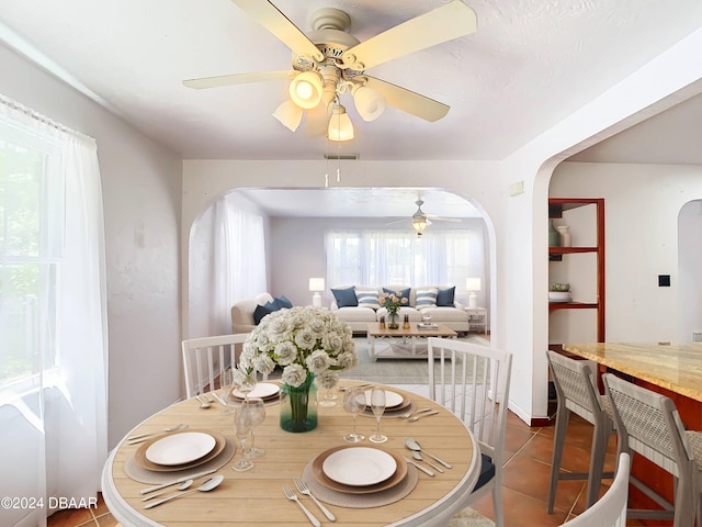 dining space featuring arched walkways, ceiling fan, tile patterned flooring, and visible vents