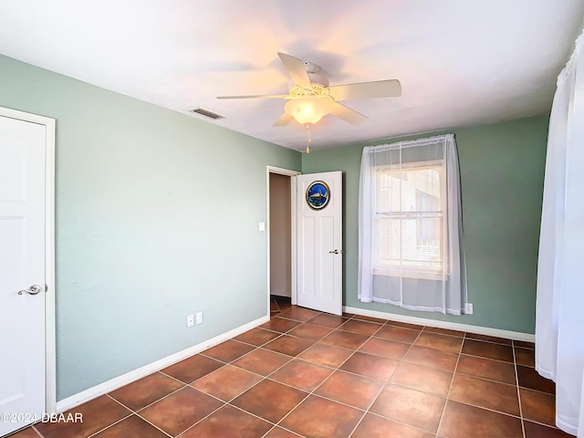 unfurnished room featuring dark tile patterned floors, visible vents, and baseboards