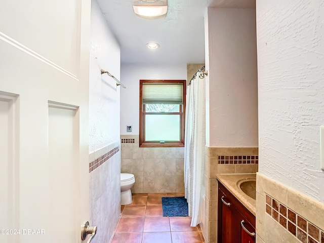 full bath featuring tile walls, toilet, wainscoting, vanity, and tile patterned flooring