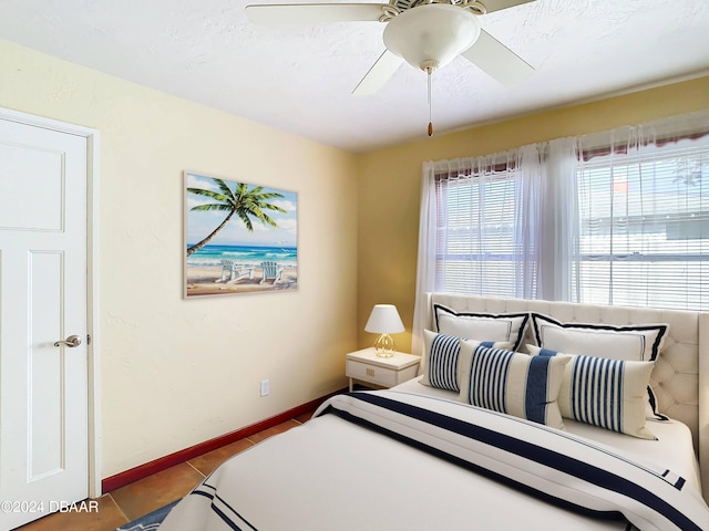 tiled bedroom featuring a ceiling fan and baseboards