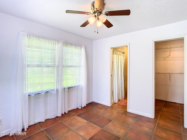 unfurnished bedroom featuring dark tile patterned floors, a ceiling fan, and baseboards