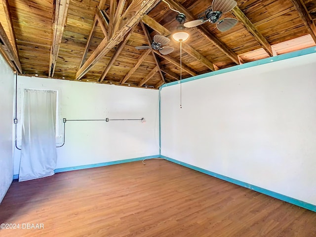 empty room with baseboards, a ceiling fan, lofted ceiling with beams, wooden ceiling, and wood finished floors