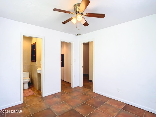 unfurnished bedroom with ceiling fan, connected bathroom, dark tile patterned flooring, visible vents, and baseboards