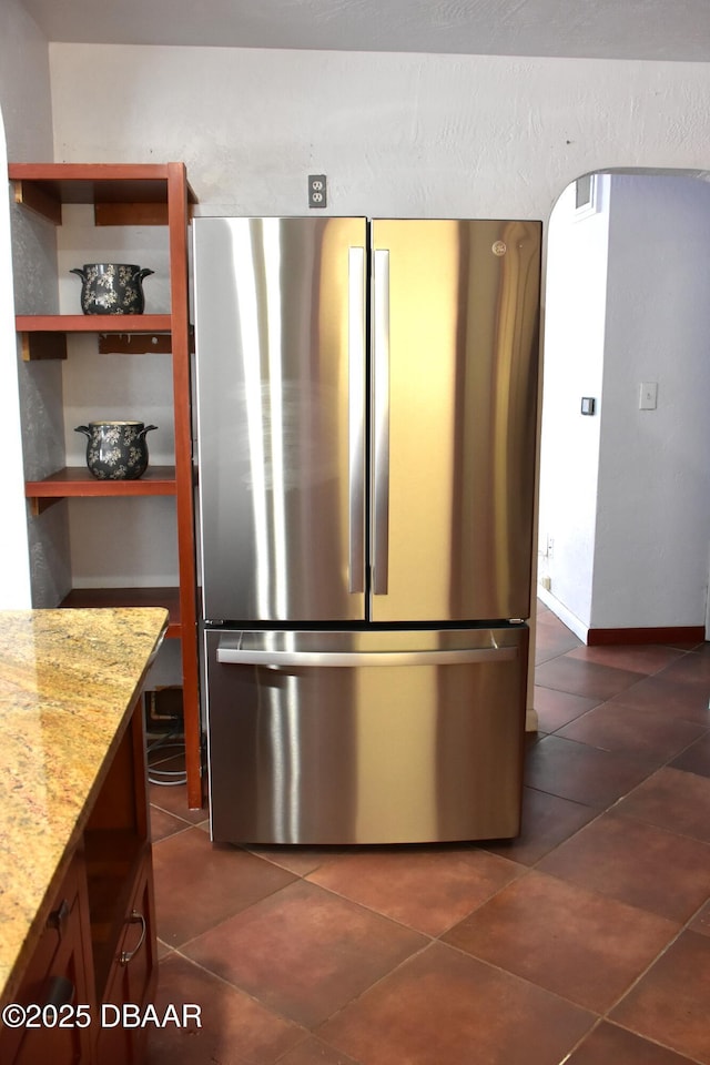 kitchen with light stone counters, dark tile patterned flooring, open shelves, and freestanding refrigerator