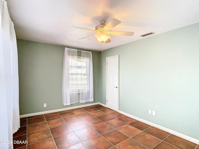 unfurnished room featuring dark tile patterned flooring, visible vents, ceiling fan, and baseboards